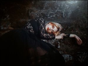 Kobieta na kamieniu w czarnej koronkowej sukience