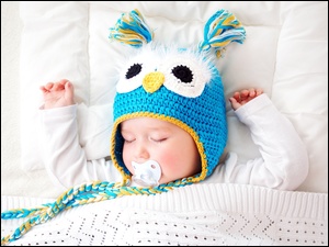 Śpiące niemowlę w czapeczce ze smoczkiem