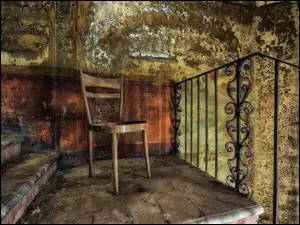 Stare zniszczone wnętrze z krzesłem stojącym na schodach obok balustrady