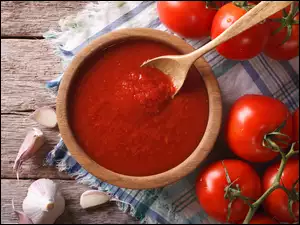 Sos pomidorowy z łyżką drewnianą obok gałązek z pomidorami