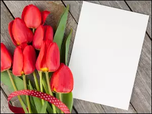 Tulipany z białą kartką na deskach