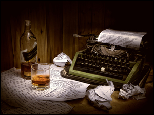 Szklanka whisky z butelką koło maszyny do pisania