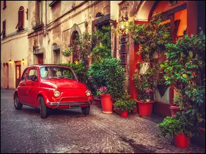 Fiat 500 na ukwieconej uliczce we Włoszech