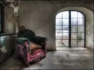 Zaniedbany pokój z fotelem i oknem