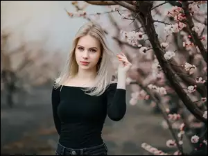 Blondynka obok kwitnącego drzewa wiśni
