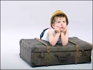 Znudzony chłopiec na walizce