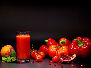 Pomidory i papryki obok szklanki z sokiem