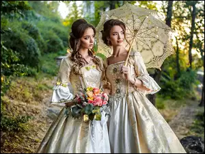 Dwie kobiety w średniowiecznej stylizacji z parasolką i kwiatami