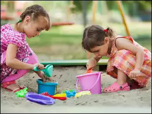 Dziewczynki z zabawkami w piaskownicy