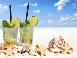 Drinki z limonką obok muszelek na plaży