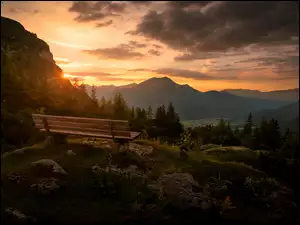 Zachód słońca nad leśnymi górami z ławeczką