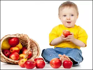 Wywrócony koszyk z jabłkami i chłopczyk który je kosztuje