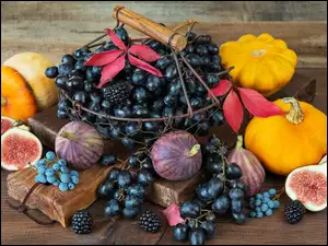 Koszyczek z winogronami obok fig i dyń na desce
