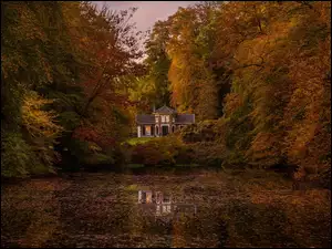 Dom nad jeziorem i drzewami jesiennymi