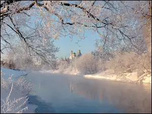 Cerkiew nad zimową rzeką z drzewami