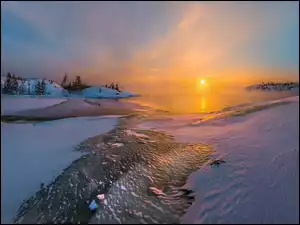 Wschód słońca nad mglistym zimowym jeziorem