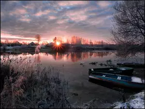 Zimowa rzeka z łódkami i drzewami