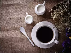 Filiżanka kawy z mlekiem i kwiatami
