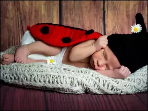 Śpiące dziecko biedronka z kwiatkami w czapce i kocyku