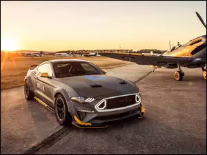 Ford Mustang GT RTR 2018 zaparkowany na lotnisku obok samolotu