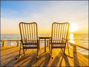 Wschód słońca nad morskim podestem z krzesłami
