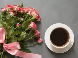 Bukiet róż obok filiżanki z kawą
