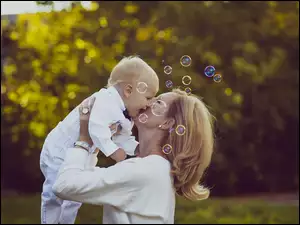 Bańki mydlane spadają na twarz kobiety i dziecka