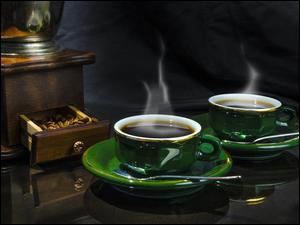Dwie filiżanki parującej kawy obok młynka