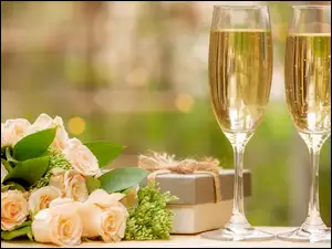 Kieliszki szampana obok prezentu i róż