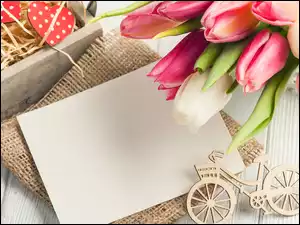 Bukiet tulipanów nad białą kartką z drewnianym rowerkiem