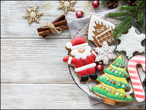 Gałązka choinki obok świątecznych ciasteczek i bombek
