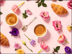 Croissanty i filiżanki kawy wśród kwiatów