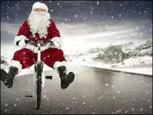 Mikołaj jadący w padającym śniegu na rowerze