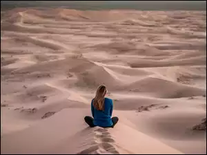Kobieta siedząca wśród piasków pustyni