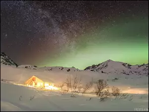 Oświetlony dom w górach Talkeetna na tle zorzy polarnej
