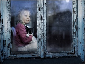 Dziewczynka z kotem patrząca przez stare okno