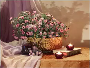 Kwiaty w koszu obok książki i świec