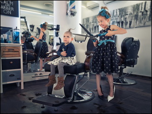 Dziewczynka z dużymi nożyczkami w zakładzie fryzjerskim