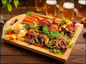 Deska mięsa i warzyw obok kufli z piwem