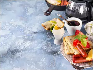 Parówki i pomidory na tostach obok herbaty w