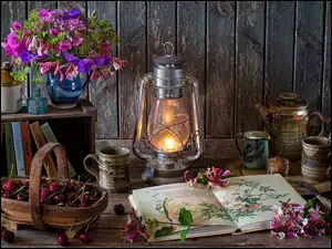 Bukiet kwiatów obok lampy, czereśni i otwartej książki