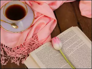 Tulipan na otwartej książce obok filiżanki kawy