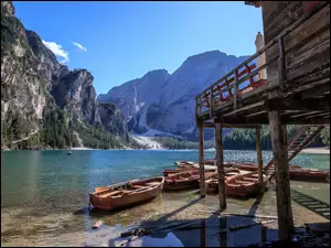 Łódki na jeziorze Pragser Wildsee przy drewnianym domku na tle włoskich Dolomitów