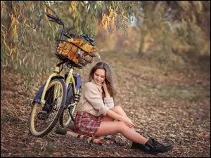 Siedząca dziewczyna na łące obok roweru