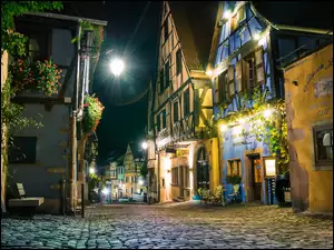 Brukowana uliczka i oświetlone nocą domy we Francji