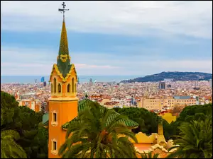Widok na wieżę wśród palm i oddalone domy Barcelony