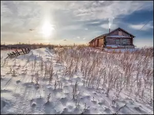 Drewniany dom na zasypanym śniegiem polu