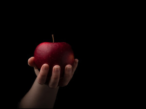 Czerwone jabłko w dłoni na ciemnym tle