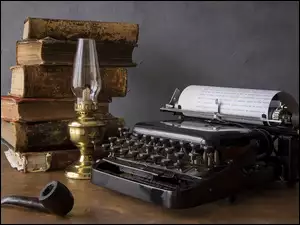 Książki i lampa obok maszyny do pisania, i rurę