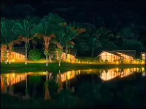 Oświetlone domki i palmy w kompleksie hotelowym Laguna Volcan w Boliwii